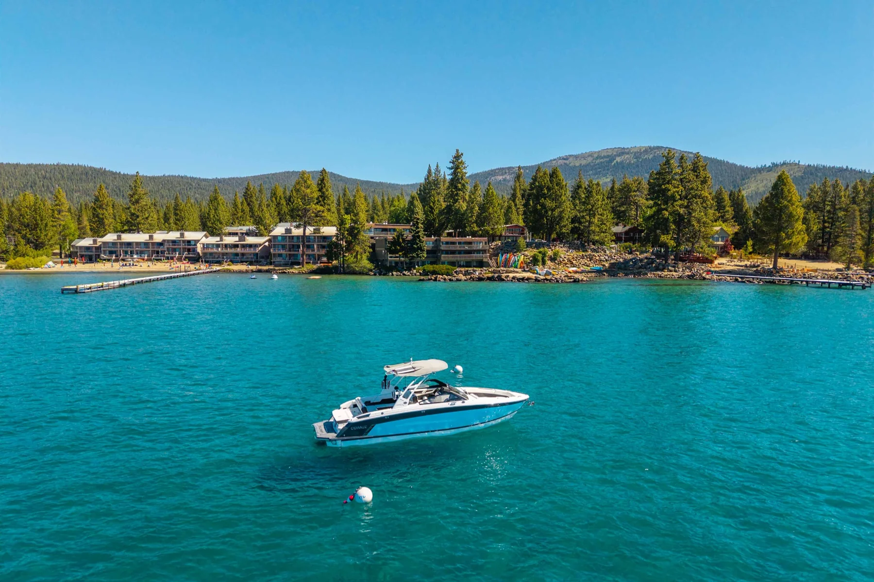 Boat on turquoise Lake Tahoe with waterfront community beyond