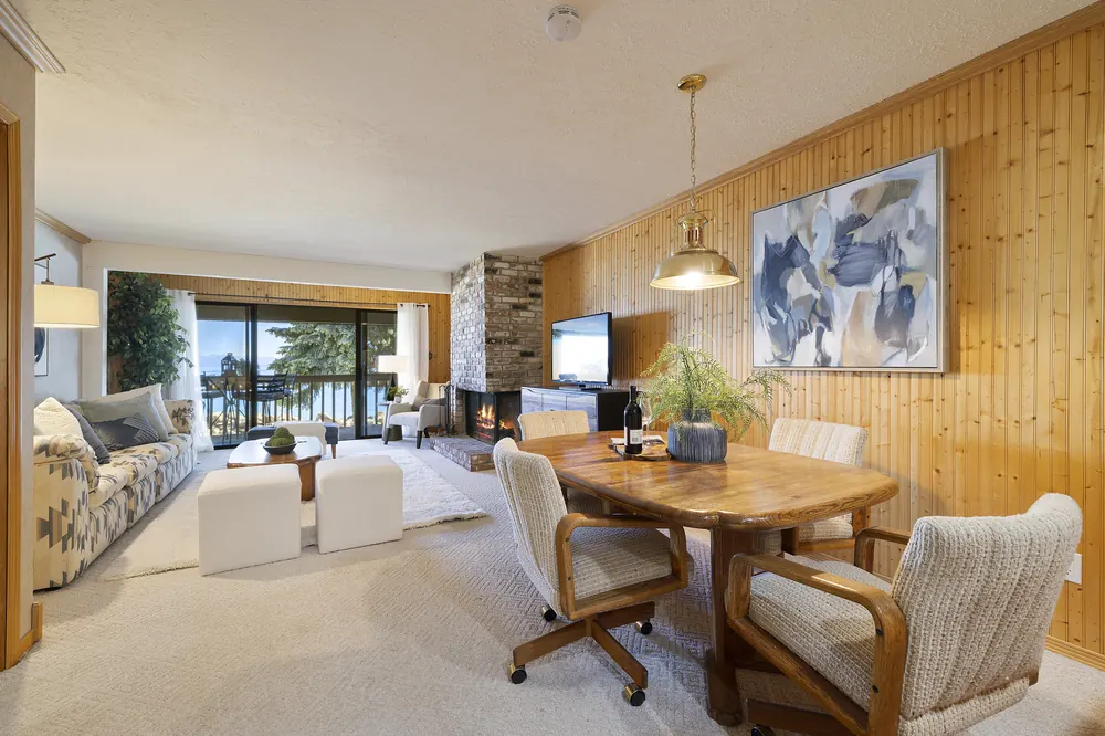 Wood-paneled great room with brick wood-burning fireplace and dining area