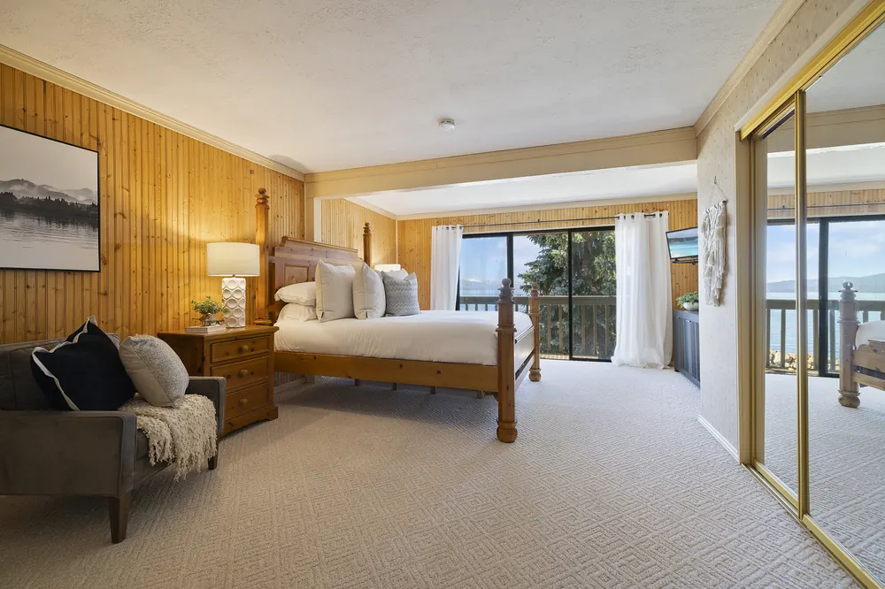 Primary bedroom opening to a private lakefront deck and water views