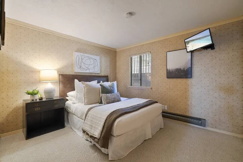 Guest bedroom with queen bed, mounted TV and forest artwork