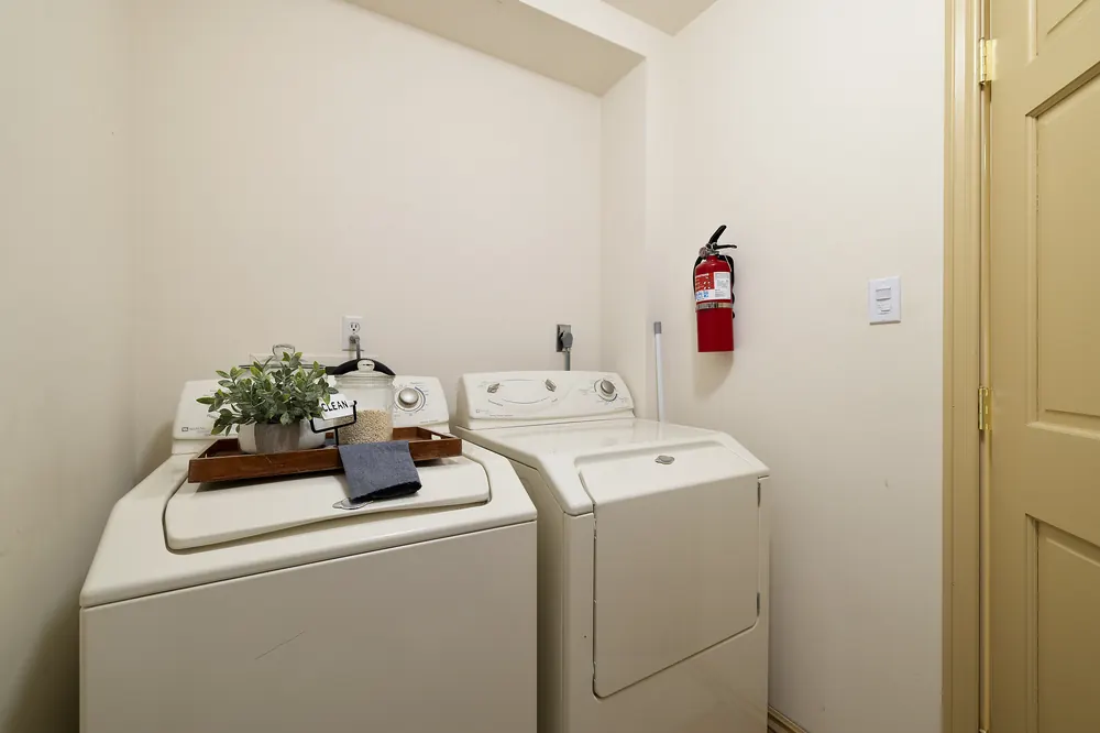 In-unit laundry closet with washer, dryer, and storage shelf